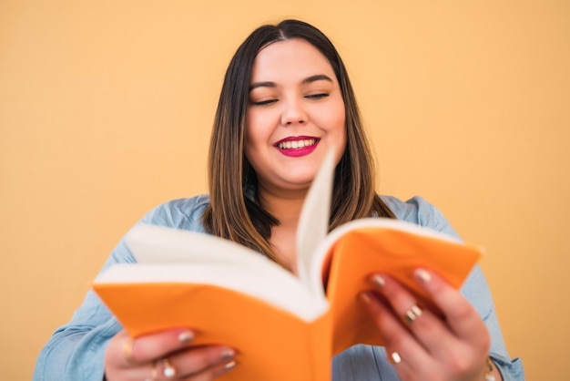 Retrato de mujer joven plus size disfrutando de tiempo libre y leyendo un libro