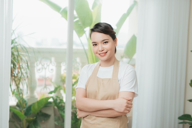 Retrato de mujer joven posando en delantal de cocina en casa