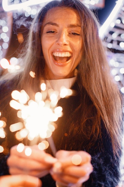 Foto retrato, de, mujer joven, posar, cerca, blanco, iluminación de navidad