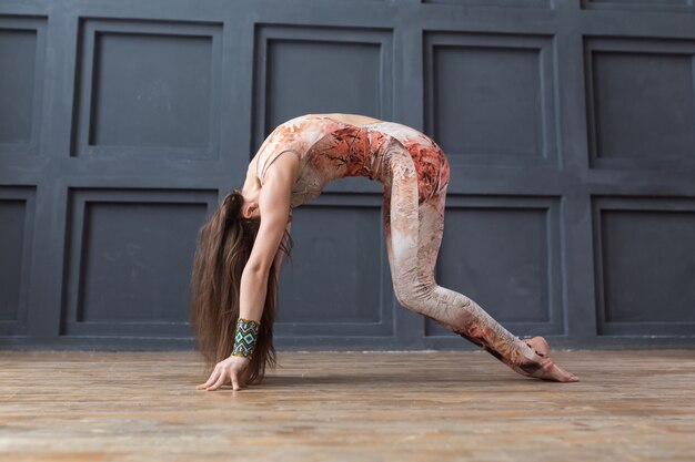 Retrato de mujer joven practicando yoga interior en pared gris urbano