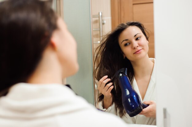 Retrato de mujer joven prety con secador de pelo.