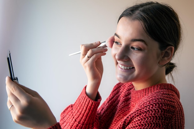 Foto retrato de una mujer joven el proceso de maquillarse con pinceles