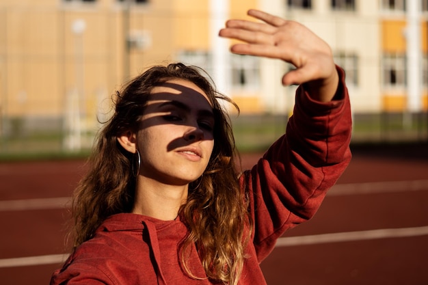 Foto retrato de una mujer joven protegiendo los ojos en la pista de atletismo