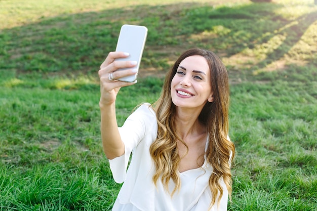 Retrato de la mujer joven que hace la foto del selfie en parque