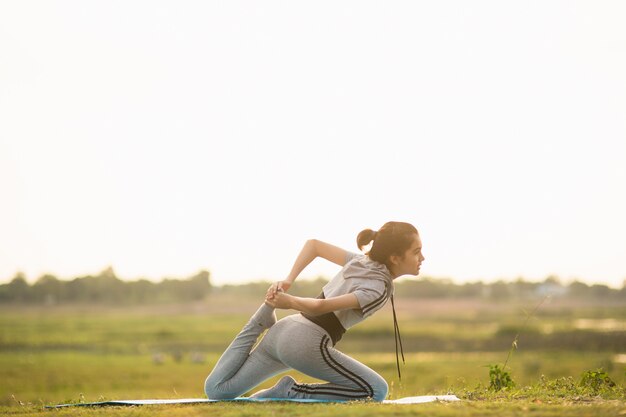 Retrato de una mujer joven que realiza yoga afuera en luz brillante soleada.