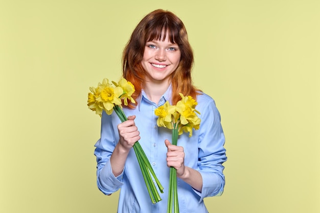 Retrato de mujer joven con ramo de flores amarillas mirando a la cámara