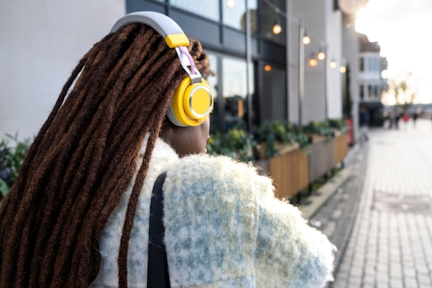 Retrato de mujer joven con rastas afro y auriculares en la ciudad