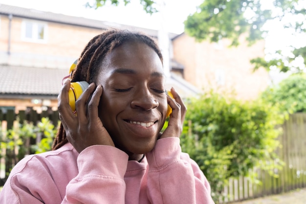 Retrato de mujer joven con rastas afro escuchando música en auriculares