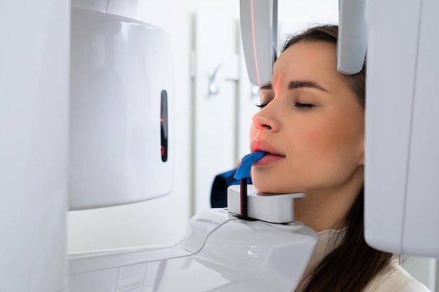 Retrato de una mujer joven con rayos X digitales panorámicos de sus dientes en el consultorio del dentista