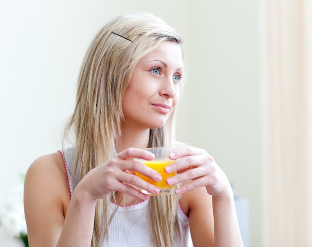 Retrato de una mujer joven relajada que bebe un zumo de naranja