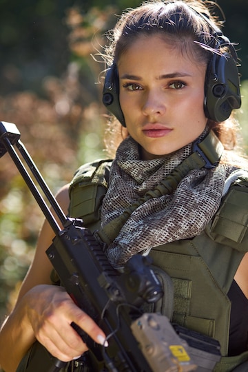 Retrato de mujer joven con arma en ropa militar al aire libre