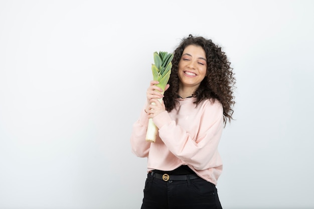 Retrato de mujer joven rizada en suéter rosa con apio.