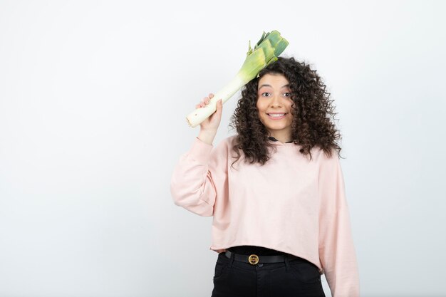 Foto retrato de mujer joven rizada en suéter rosa con apio.