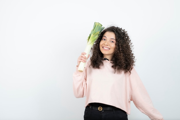 Retrato de mujer joven rizada en suéter rosa con apio.