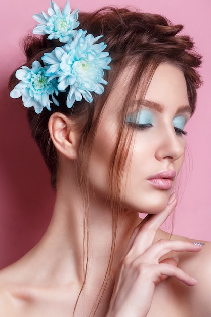 Retrato de mujer joven romántica con flor azul mirando. Foto de moda de primavera. Inspiración de primavera y verano.