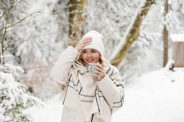 Retrato de mujer joven en ropa de abrigo en el bosque de invierno Bebiendo té caliente al aire libre del termo Senderismo Turismo