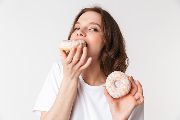 Retrato de una mujer joven satisfecha comiendo una rosquilla