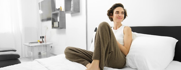 Foto retrato de una mujer joven sentada en la cama en casa