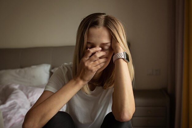 Foto retrato de una mujer joven sentada en la cama en casa