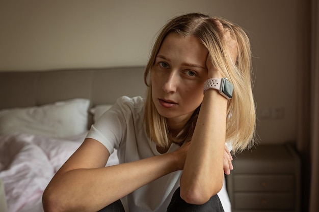 Retrato de una mujer joven sentada en la cama en casa