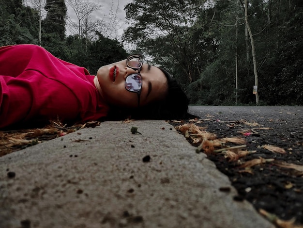 Foto retrato de una mujer joven sentada en la carretera