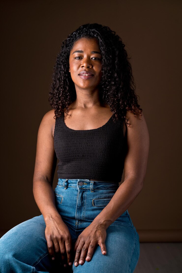 Foto retrato de una mujer joven sentada contra un fondo negro