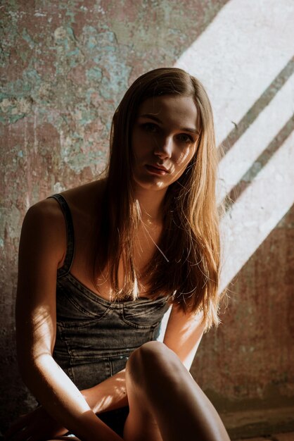 Foto retrato de una mujer joven sentada contra la pared