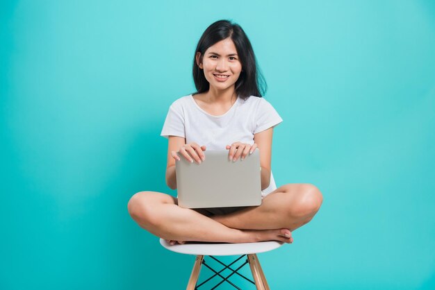 Foto retrato de una mujer joven sentada en una silla contra un fondo azul