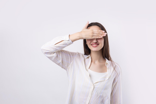 Retrato de una mujer joven seria que muestra un gesto de parada con la palma de la mano sobre fondo blanco.