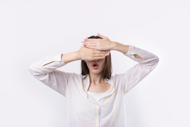 Retrato de una mujer joven seria que muestra un gesto de parada con la palma de la mano sobre fondo blanco.