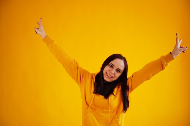 Foto retrato de mujer joven sobre fondo amarillo bonita morena con capucha amarilla posando sobre fondo brillante