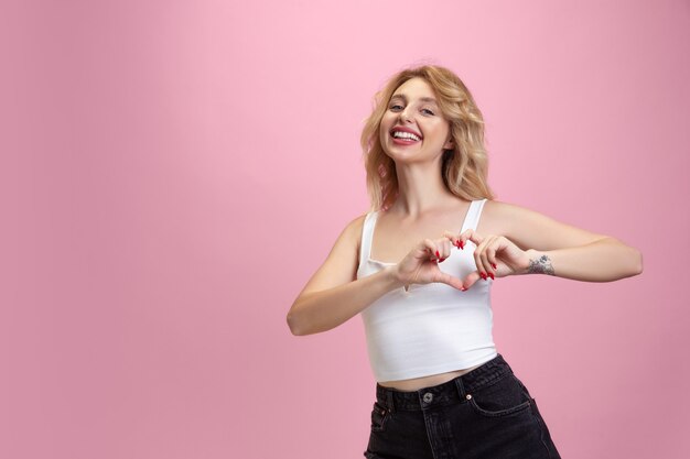 Retrato de mujer joven sobre fondo rosa studio. Hermosa modelo rubia