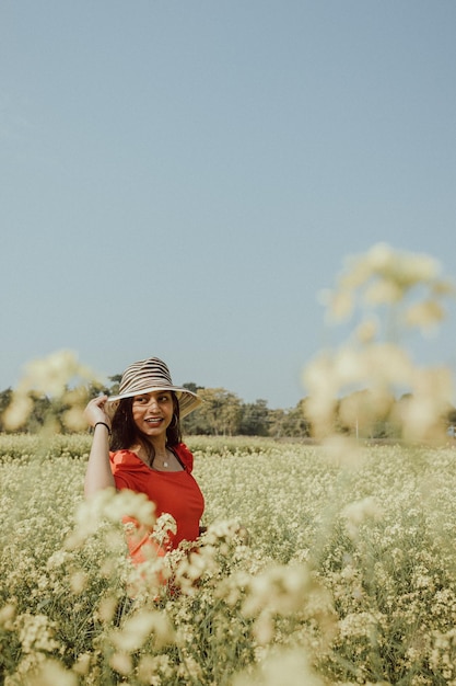 Foto retrato de una mujer joven con sombrero en el campo contra un cielo despejado