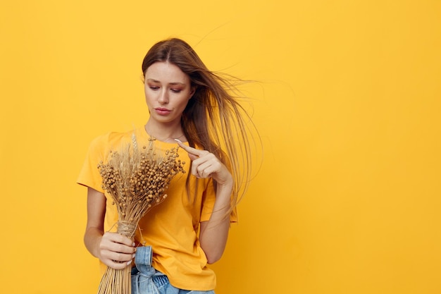 Retrato de una mujer joven con sombrero flores secas estilo verano fondo amarillo