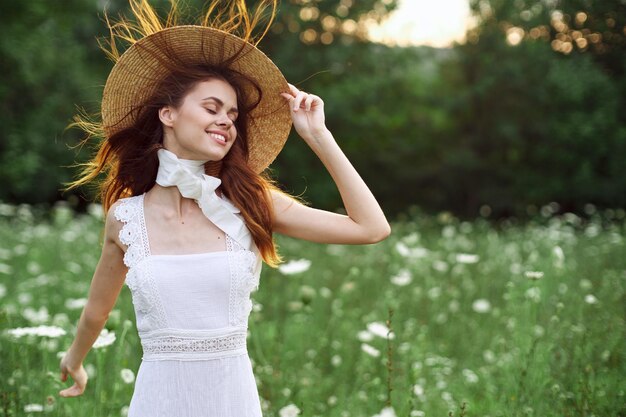 Foto retrato de una mujer joven con sombrero de pie contra las plantas