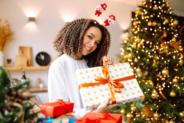 Retrato de mujer joven con sombrero de santa claus con regalo en el árbol de Navidad Navidad Año Nuevo