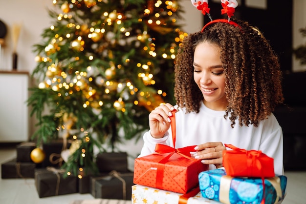 Retrato de mujer joven con sombrero de santa claus con regalo en el árbol de Navidad Navidad Año Nuevo