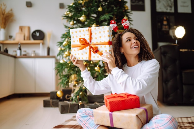 Retrato de mujer joven con sombrero de santa claus con regalo en el árbol de Navidad Navidad Año Nuevo