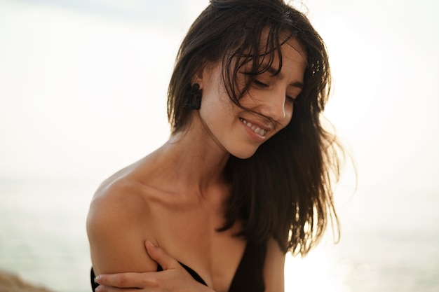 Retrato de mujer joven sonriente al aire libre en la playa