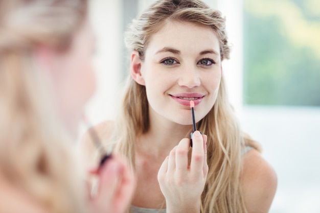 Retrato de mujer joven sonriente aplicar brillo labial