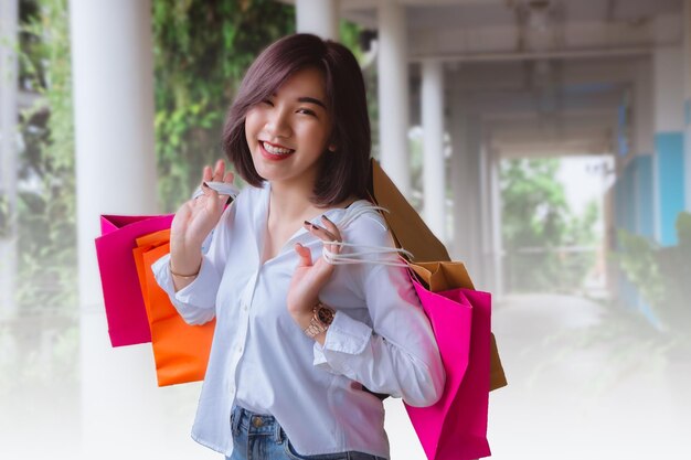 Retrato de una mujer joven sonriente con bolsas de compras de pie al aire libre
