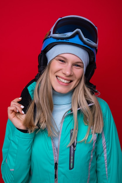 Retrato de una mujer joven sonriente en una chaqueta, casco y gafas de esquí