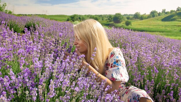 Retrato de mujer joven sonriente que huele flores en campo de lavanda en la Provenza.