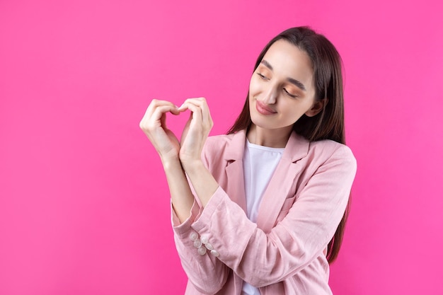 Retrato de una mujer joven sonriente que muestra un gesto de corazón con los dedos aislado sobre fondo pikn