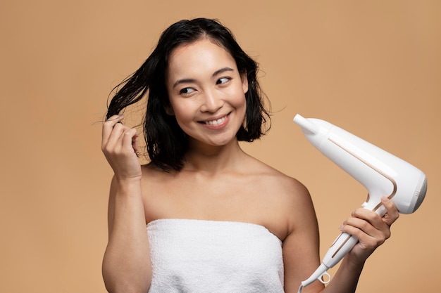 Retrato de mujer joven sonriente seca su cabello sobre fondo beige