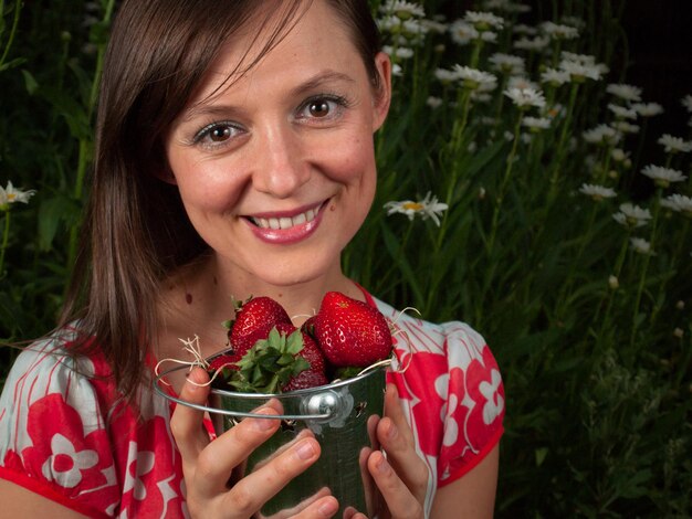 Retrato de una mujer joven sonriente sosteniendo fresas.