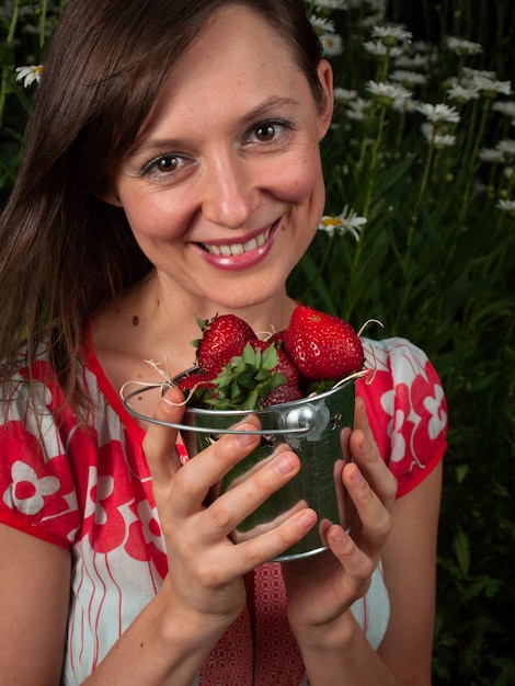 Retrato de una mujer joven sonriente sosteniendo fresas.