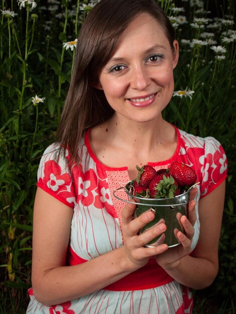 Retrato de una mujer joven sonriente sosteniendo fresas.