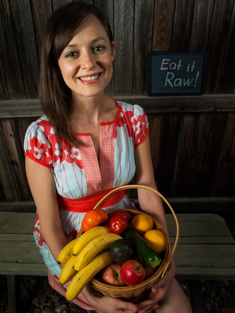 Retrato de una mujer joven sonriente sosteniendo verduras en la canasta.