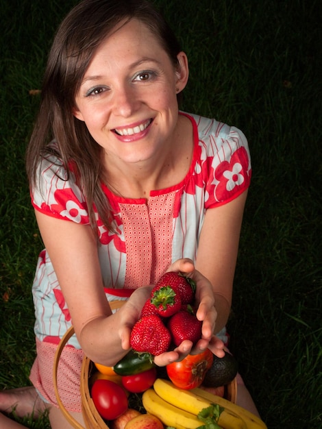 Retrato de una mujer joven sonriente sosteniendo verduras en la canasta.